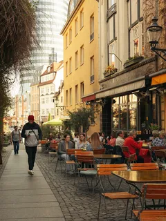 Mann geht am Gehsteig neben Tischen und Stühlen entlang