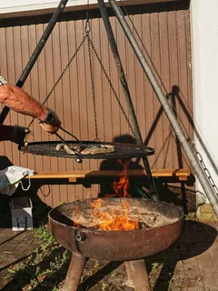Würste werden auf dem Schwenker Grill über offenem Feuer gegrillt