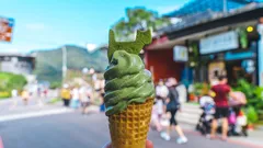 Hand hält ein Eis am Stiel vor blauem Hintergrund